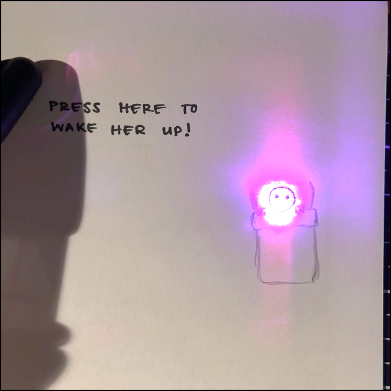 Drew a simple drawing of someone sleeping in bed with eyes and mouth closed, when the light turns on, the light illuminates the drawing from behind and the person's eyes and mouth opens in surprise. However, because the light was so close to the paper, it was concentrated in one section and made the drawing difficult to see.