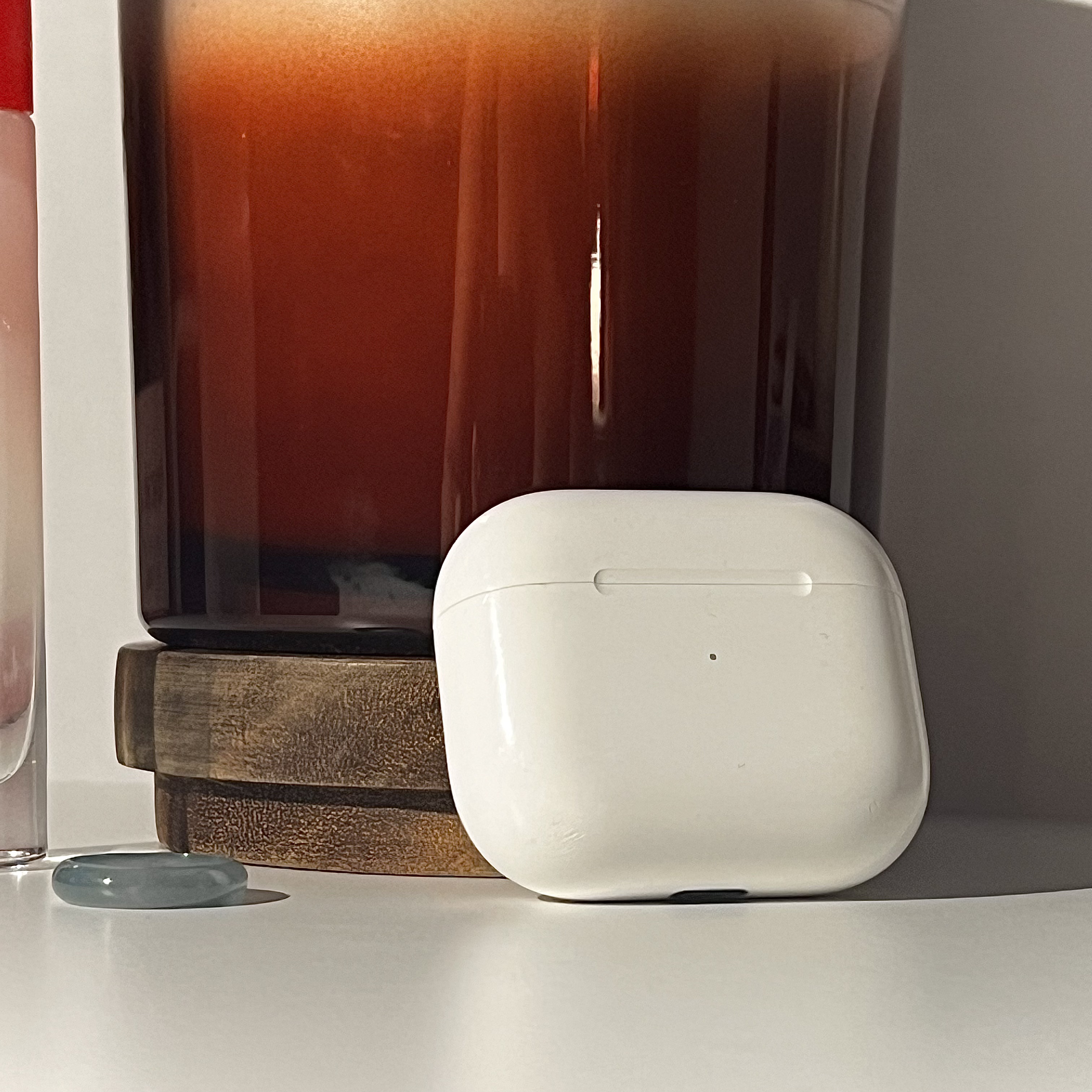 a photo of airpods leaning against a candle